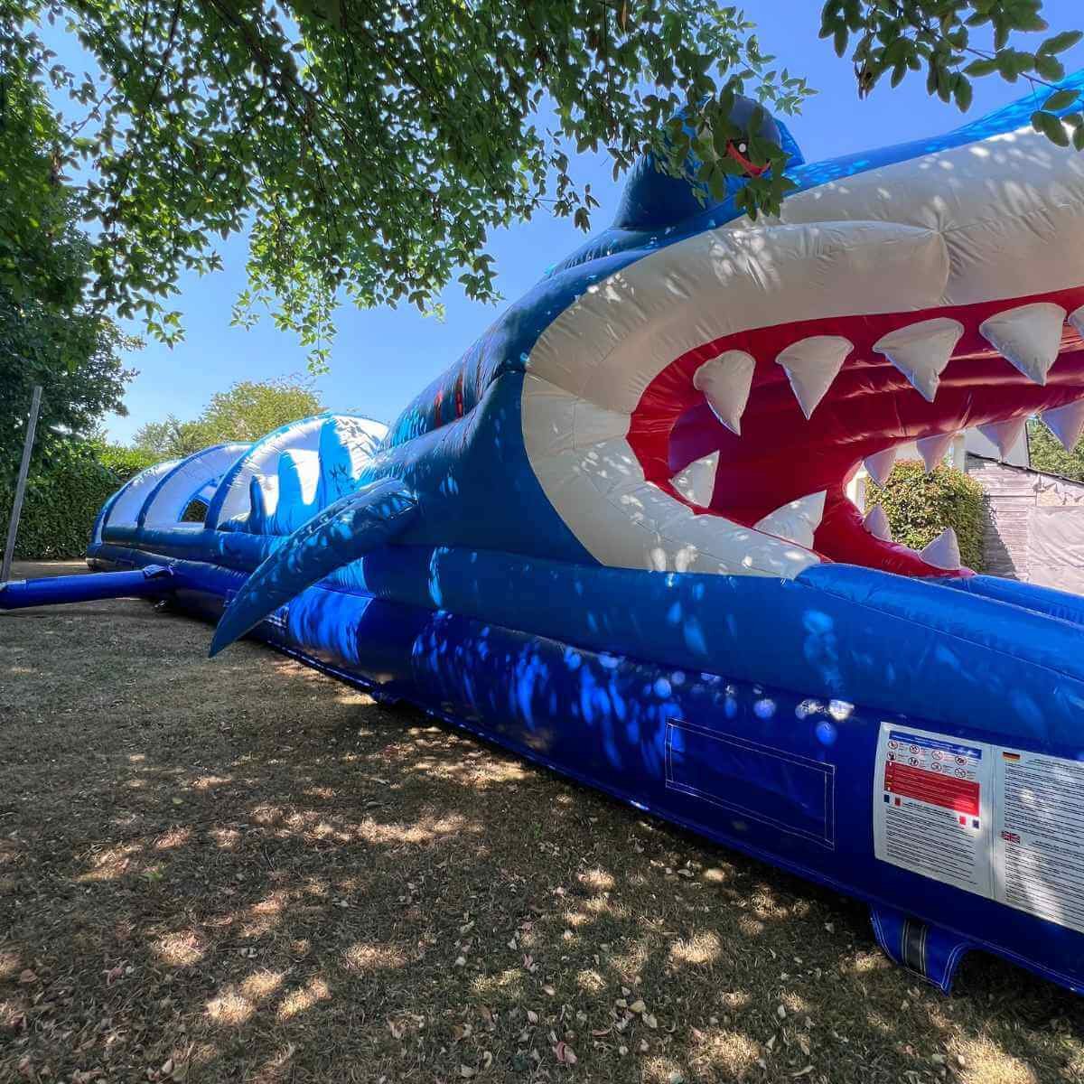 Ventriglisse gonflable géant de 15 m à entrée en gueule de requin, installé sur une pelouse en Normandie